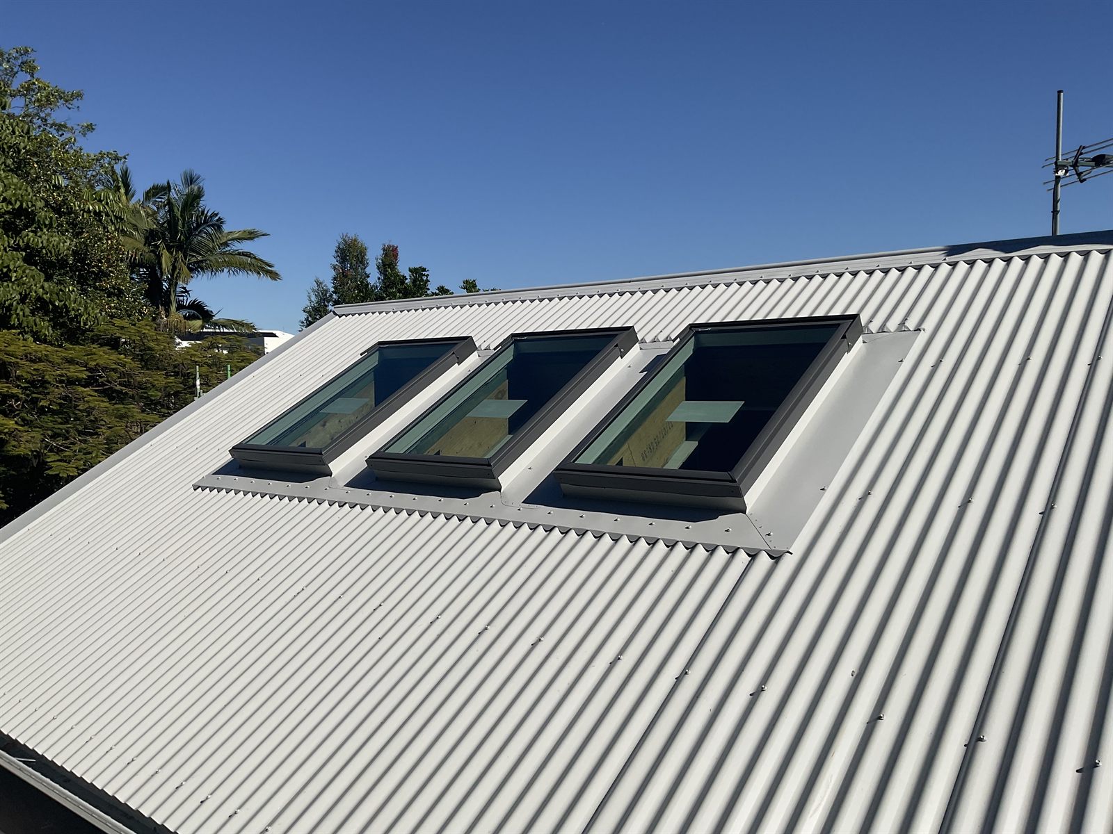 Three Velux roof windows installed in a row with custom Colorbond flashings
